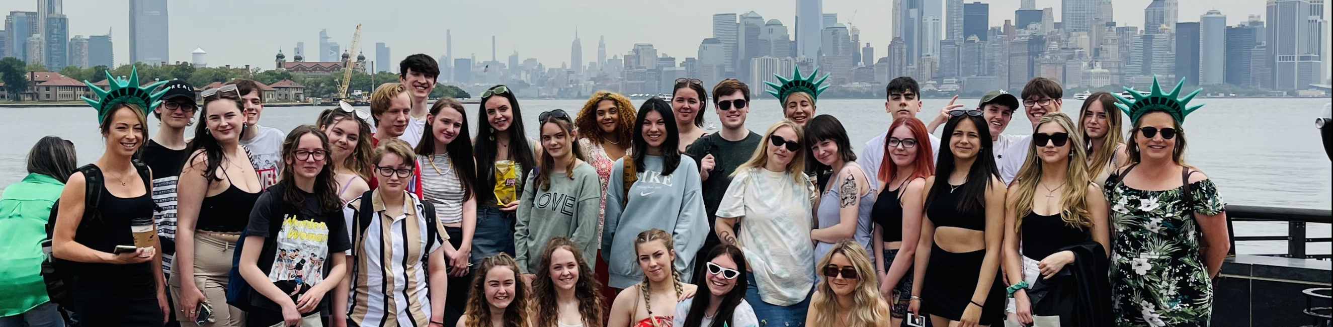 performing arts students stood next to the statue of liberty in new york