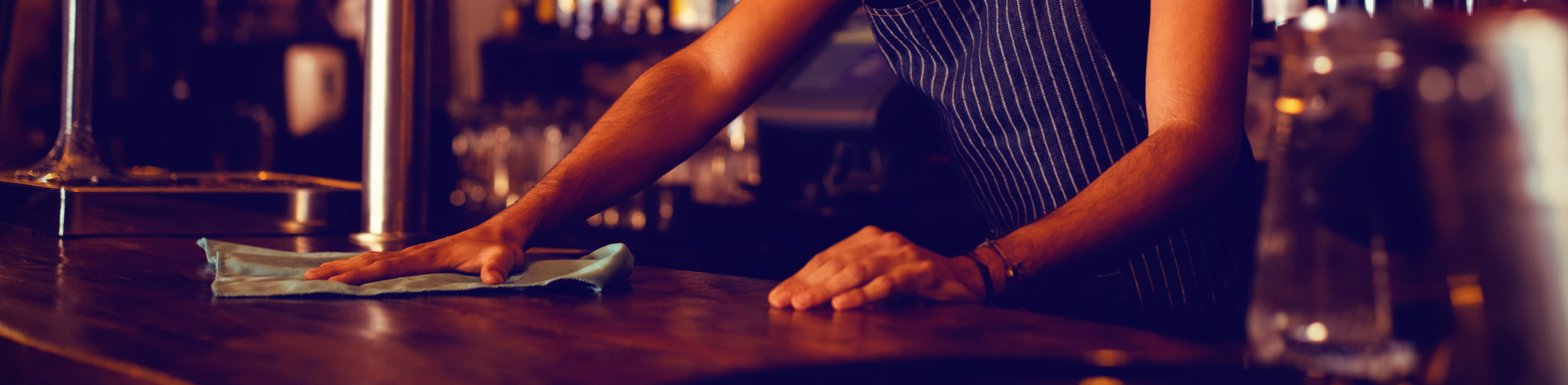Waiter cleaning counter top in pub
