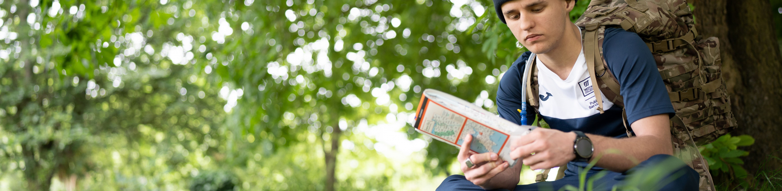 a student sitting next to a tree with a map