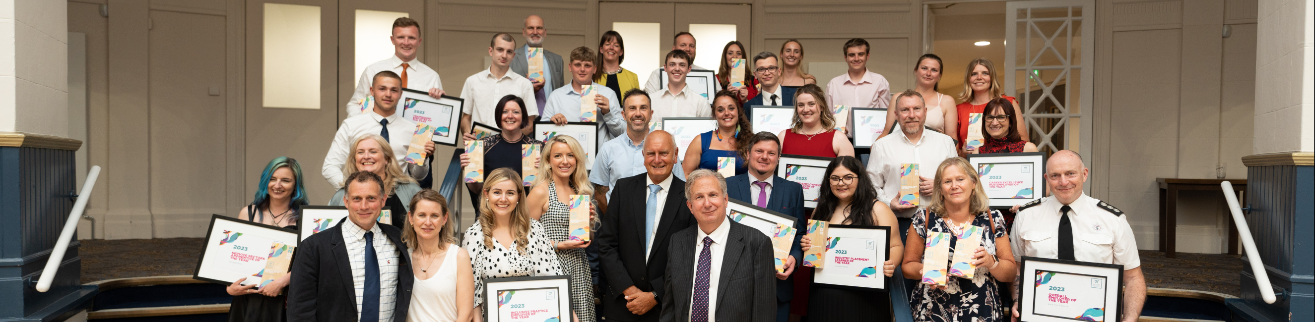 The winners of Weston College Business Awards gathered together on steps showcasing awards