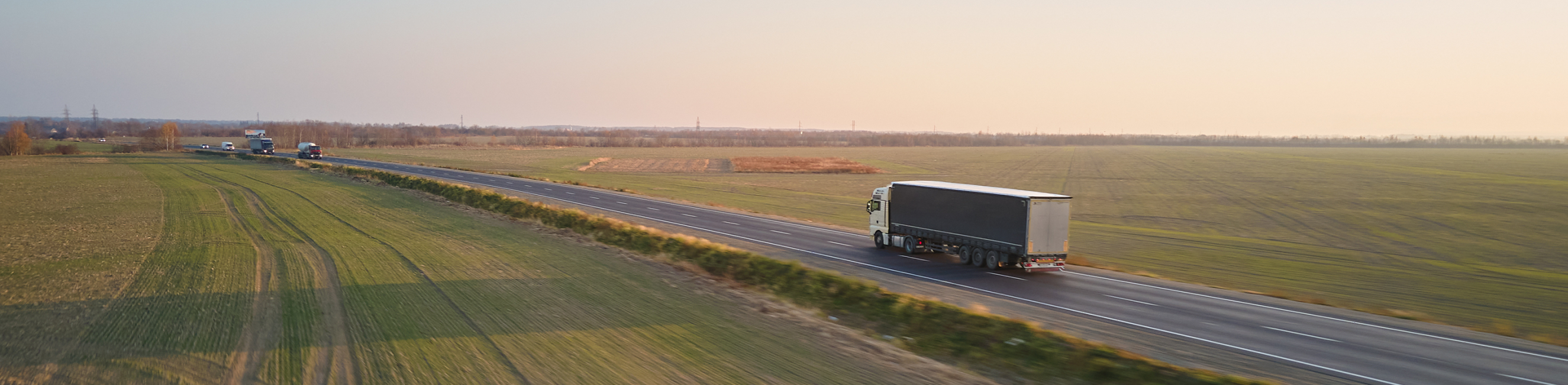 Lorry driving on the road passed some fields