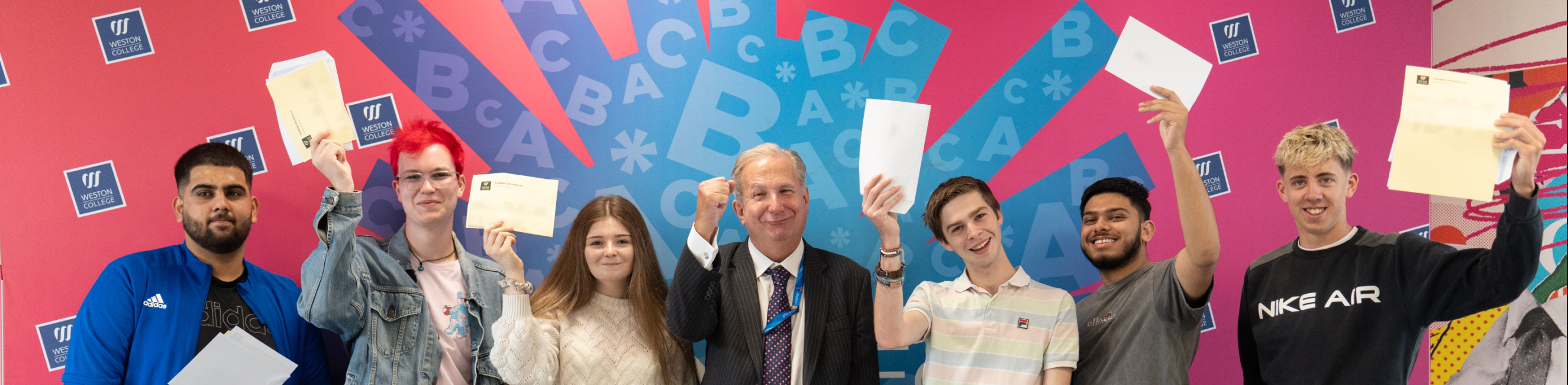 Learners Celebrating their A Level Results, holding up their papers with Sir Paul Phillips stood in the middle. 