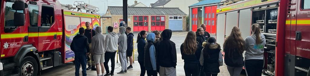 Learners listening to a talk stood by fire engines