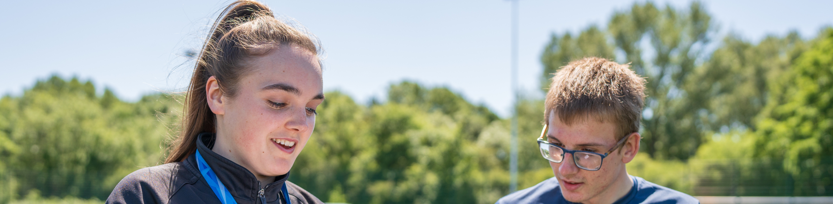 A Weston College sport lecturer on the sports field with a student both looking at a clipboard