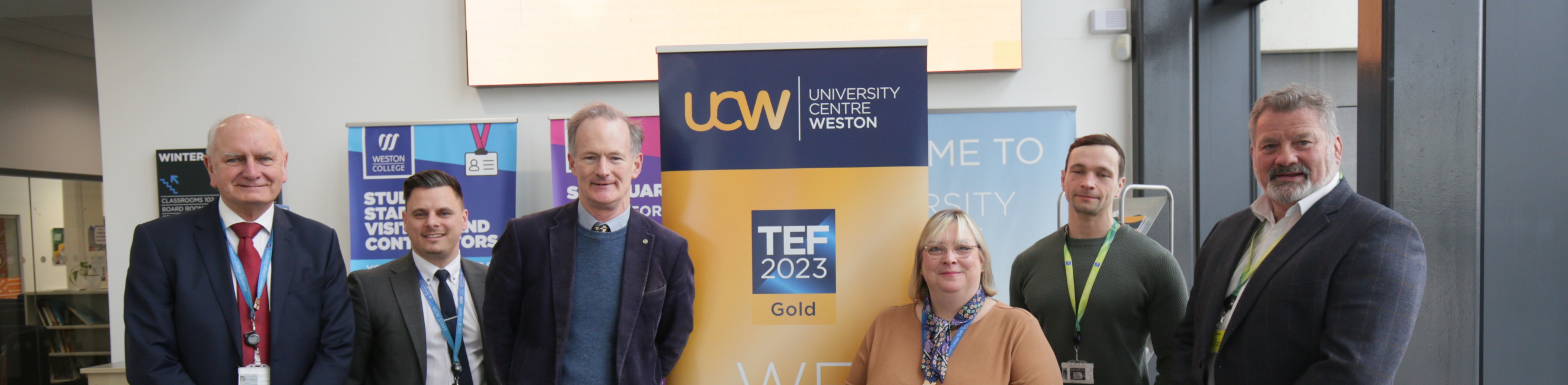 John Penrose, Andrew Leighton-Price and others stand by a sign saying UCW 'TEF Gold'