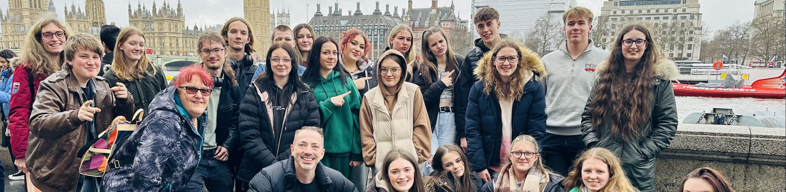 Performing arts students and teachers posing in front of the thames river, parliament and the big ben in London
