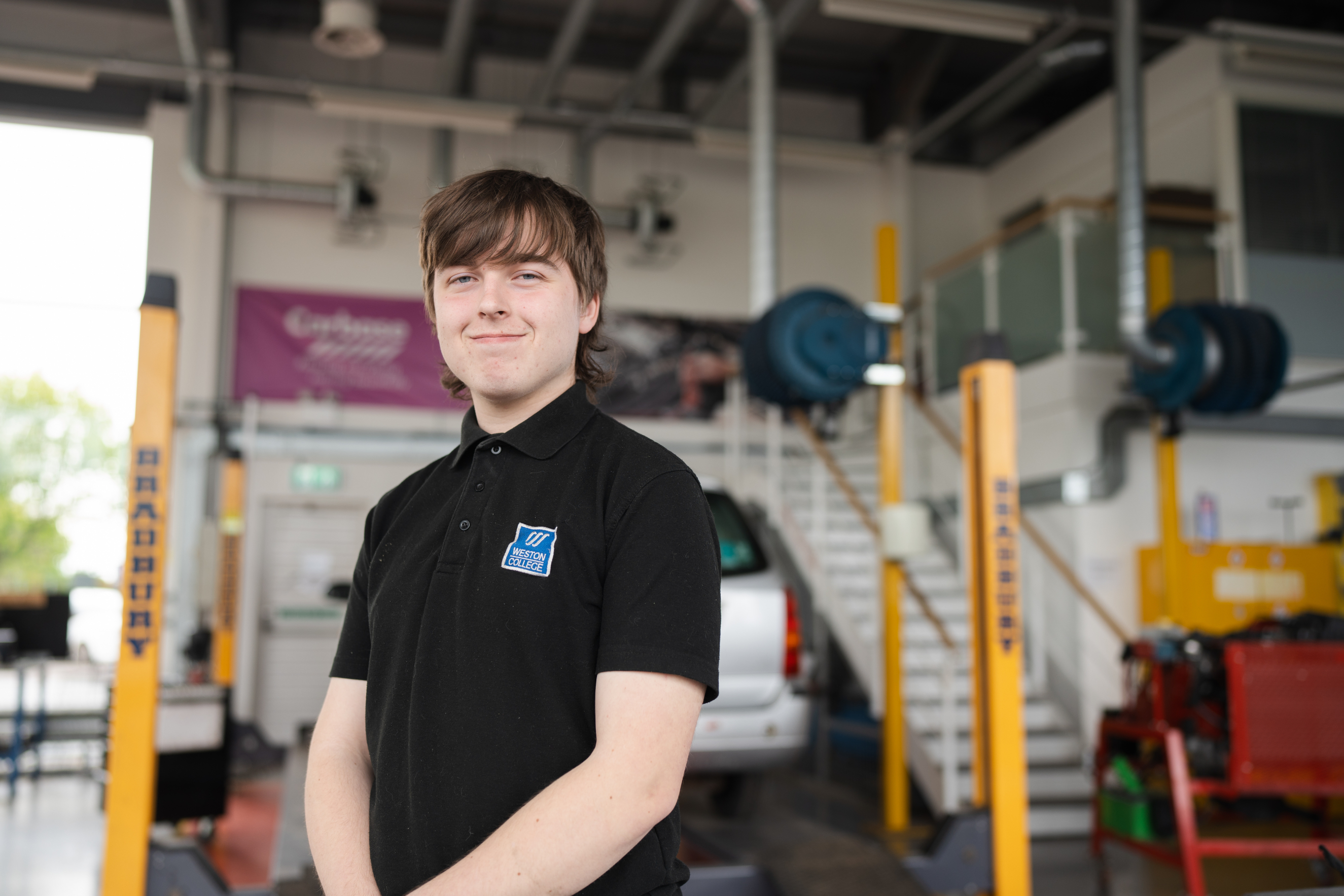 Student smiling at camera in an automotive workshop