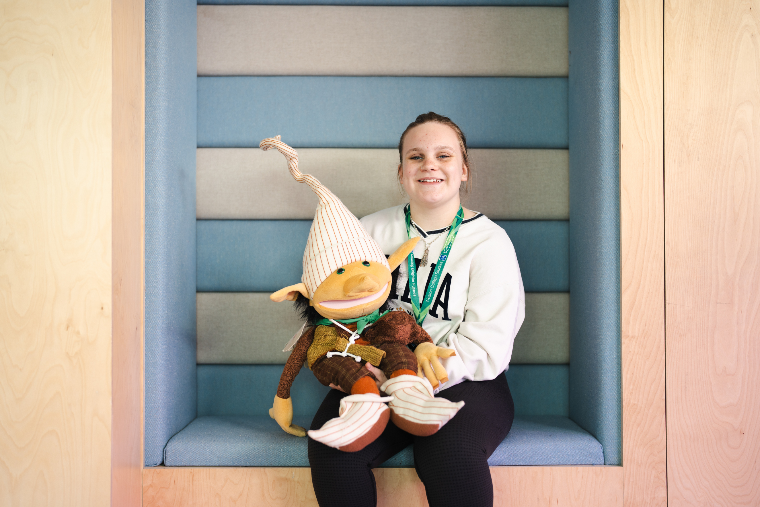 female early years student smiling while holding a puppet
