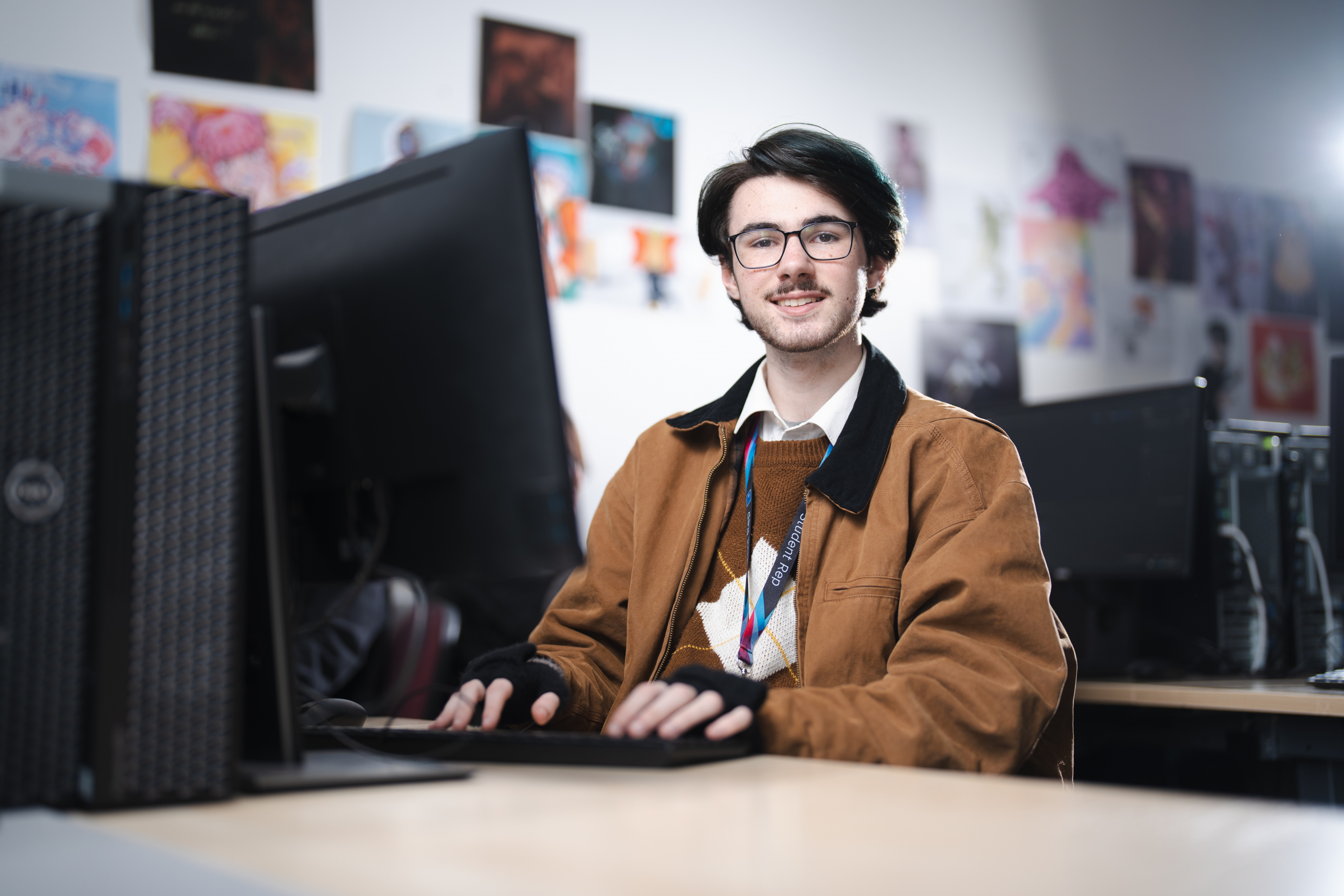 Learner smiling at the camera as he works on a computer