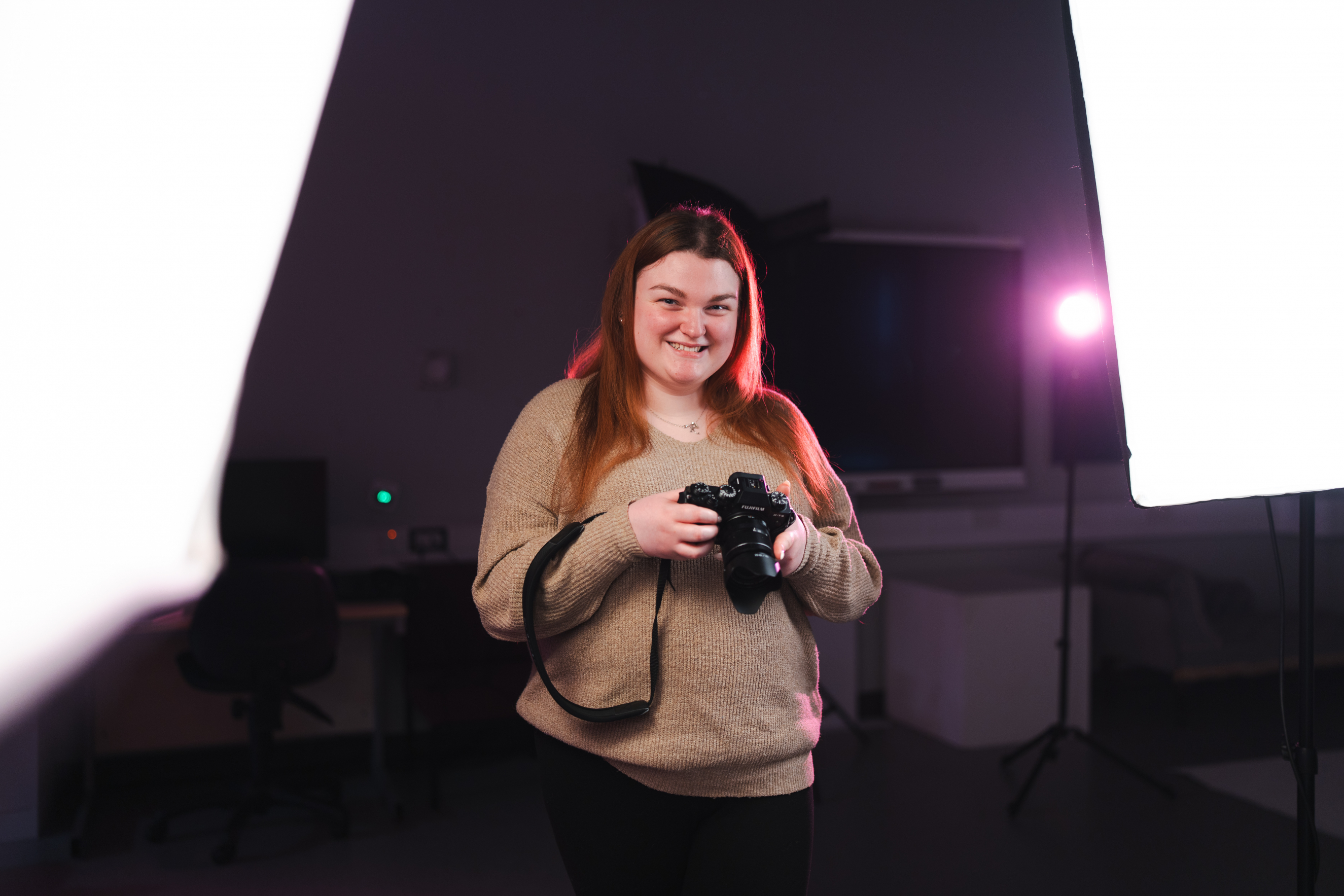 Student smiling holding camera