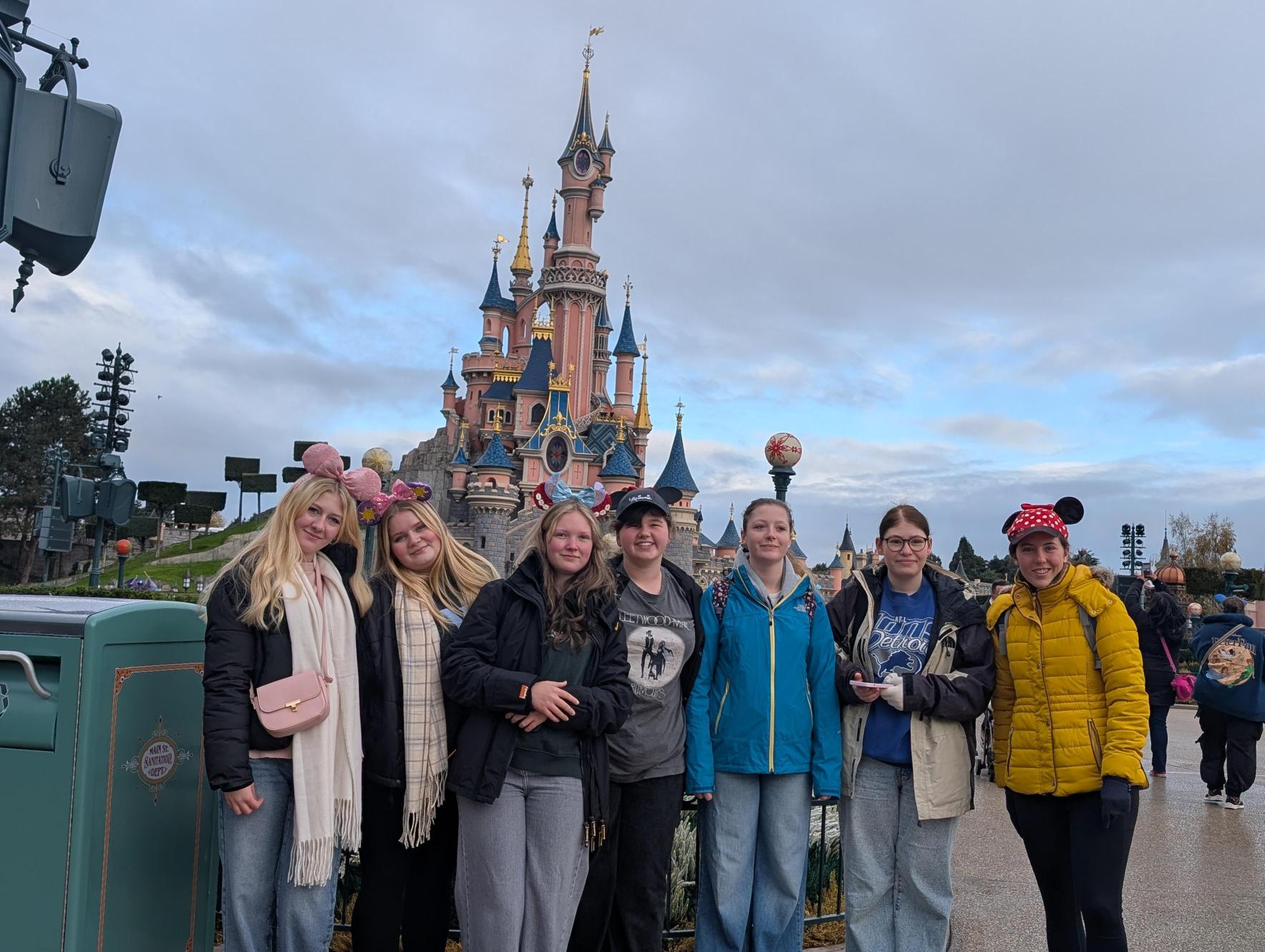 Students smiling by the Disney castle
