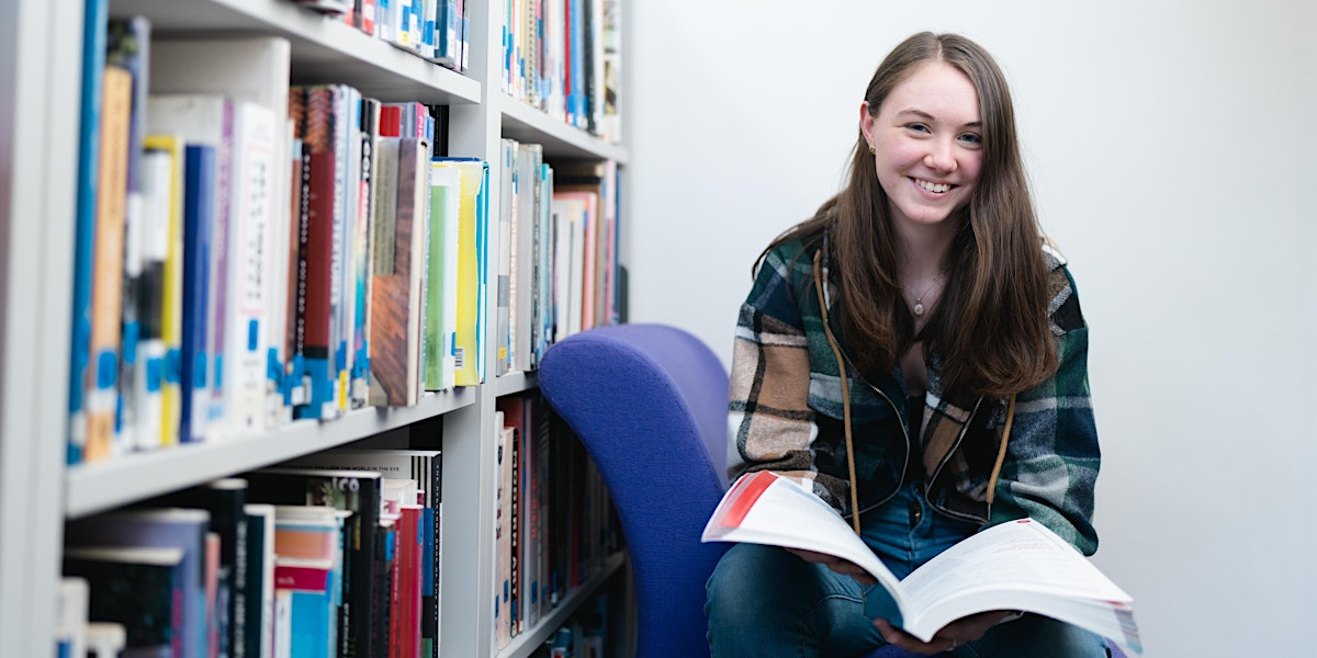sixth form learner reading a book in the library