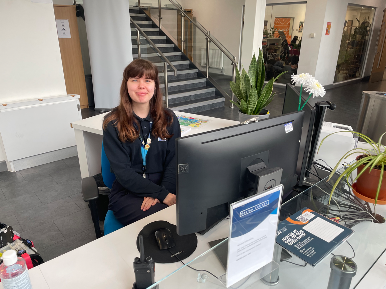 India sat behind the reception desk smiling