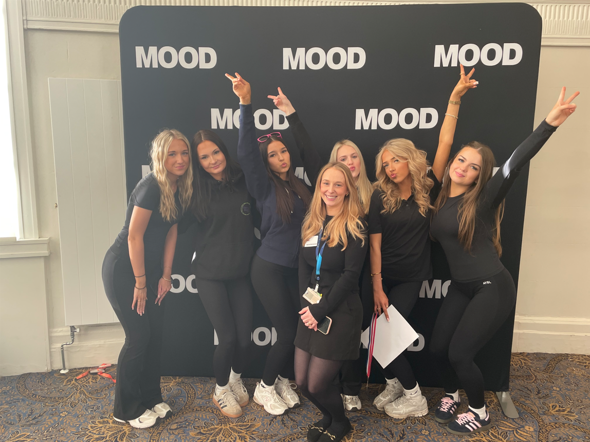Group of students smiling in front of sponsored backdrop