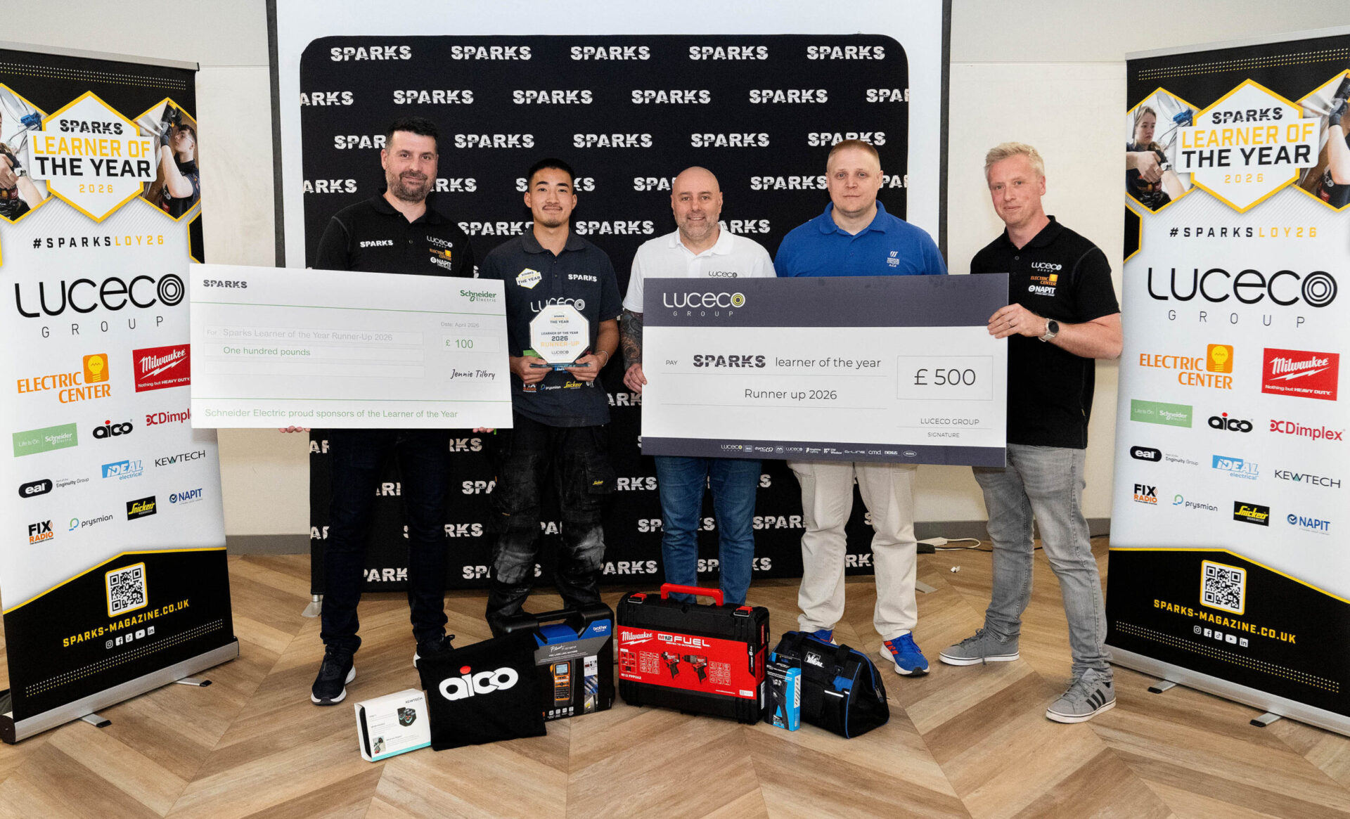 Marcus holding cheque and prizes with 4 industry professionals