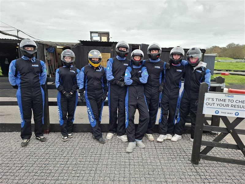 Students standing wearing their go-karting uniforms in front of the track