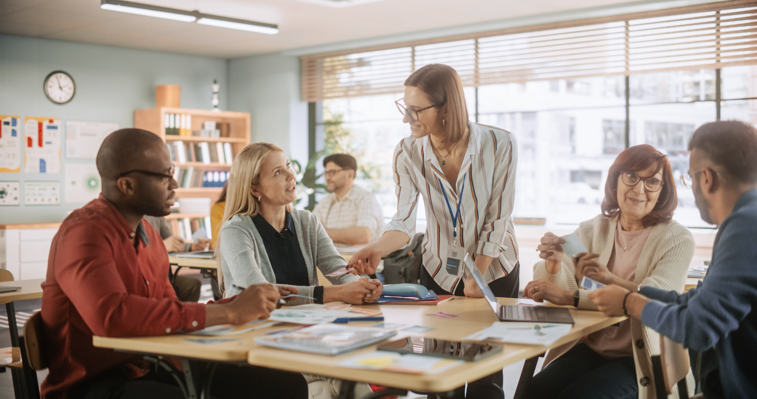 Adult learners sat around classroom table with teacher
