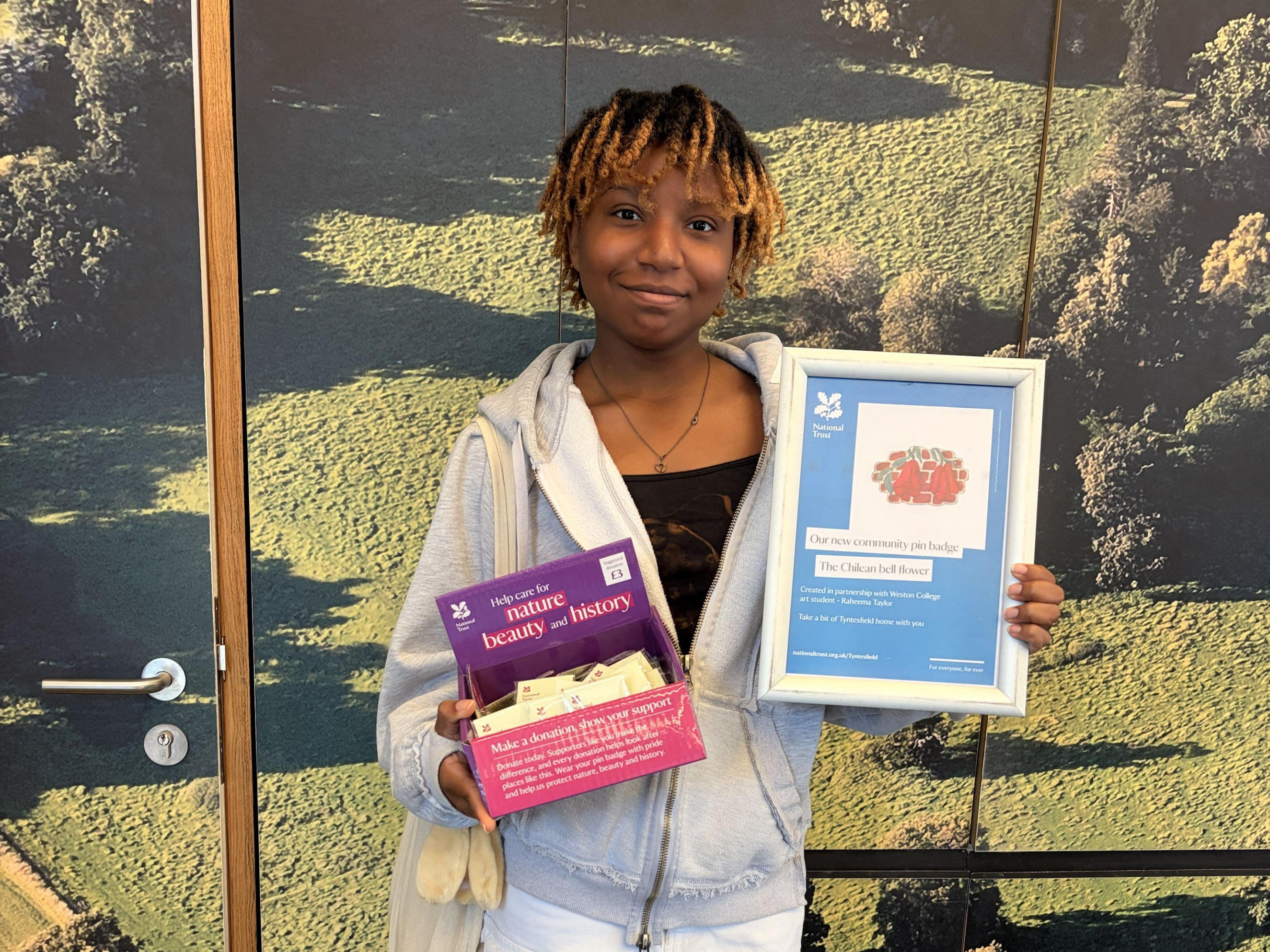 Student, Raheema, standing with a certificate and her pin badges