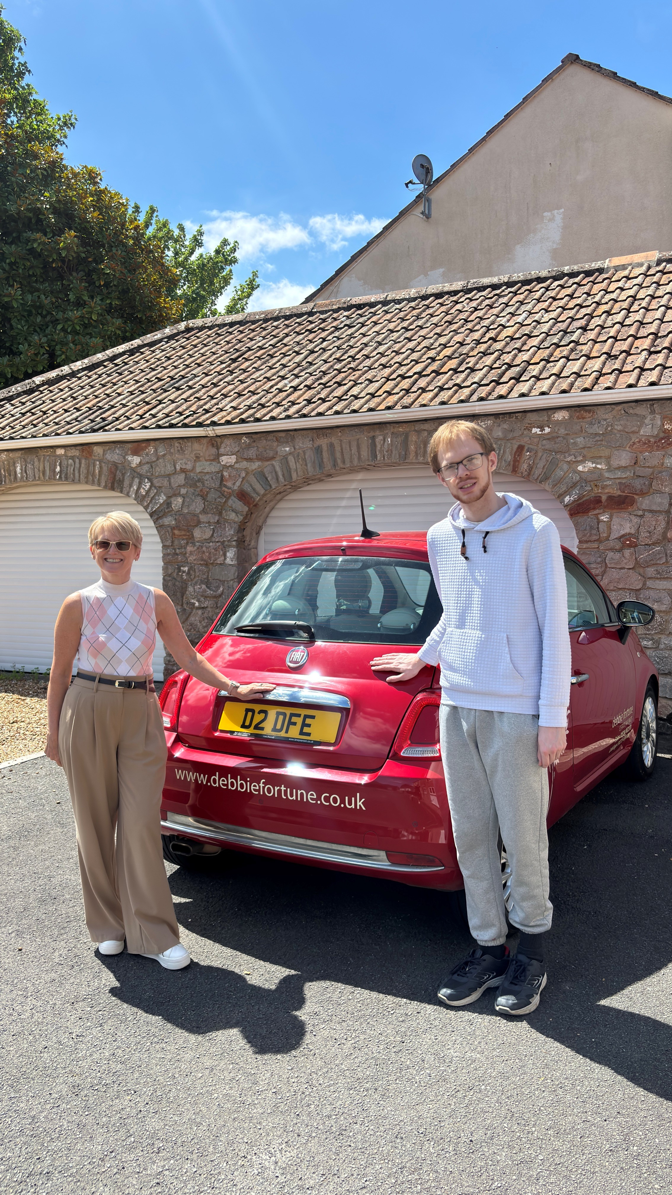 Jo and Kyle stood smiling by a debbie fortune estate agents car