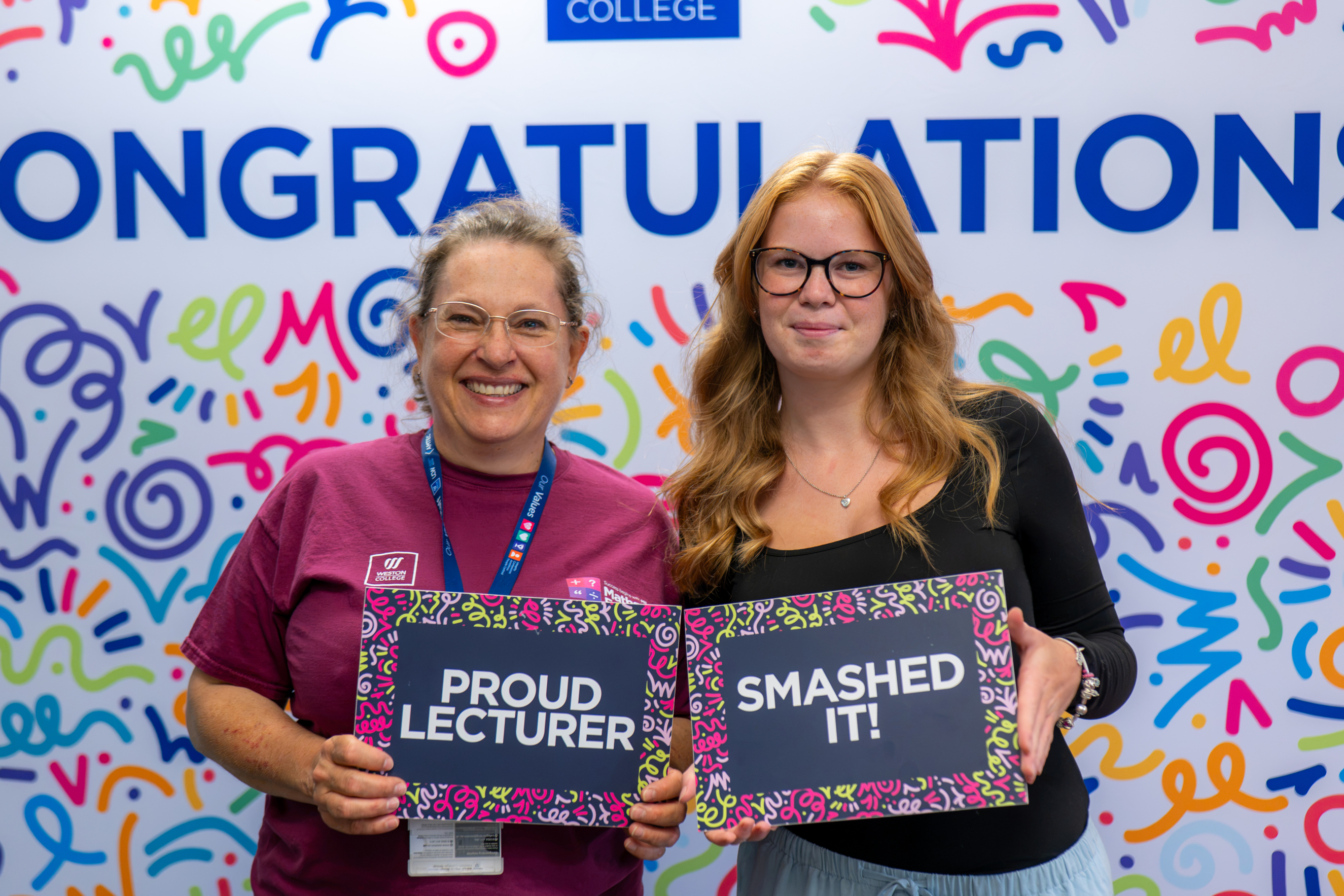 Student and Lecturer holding sings saying: Proud Lecturer and Smashed It