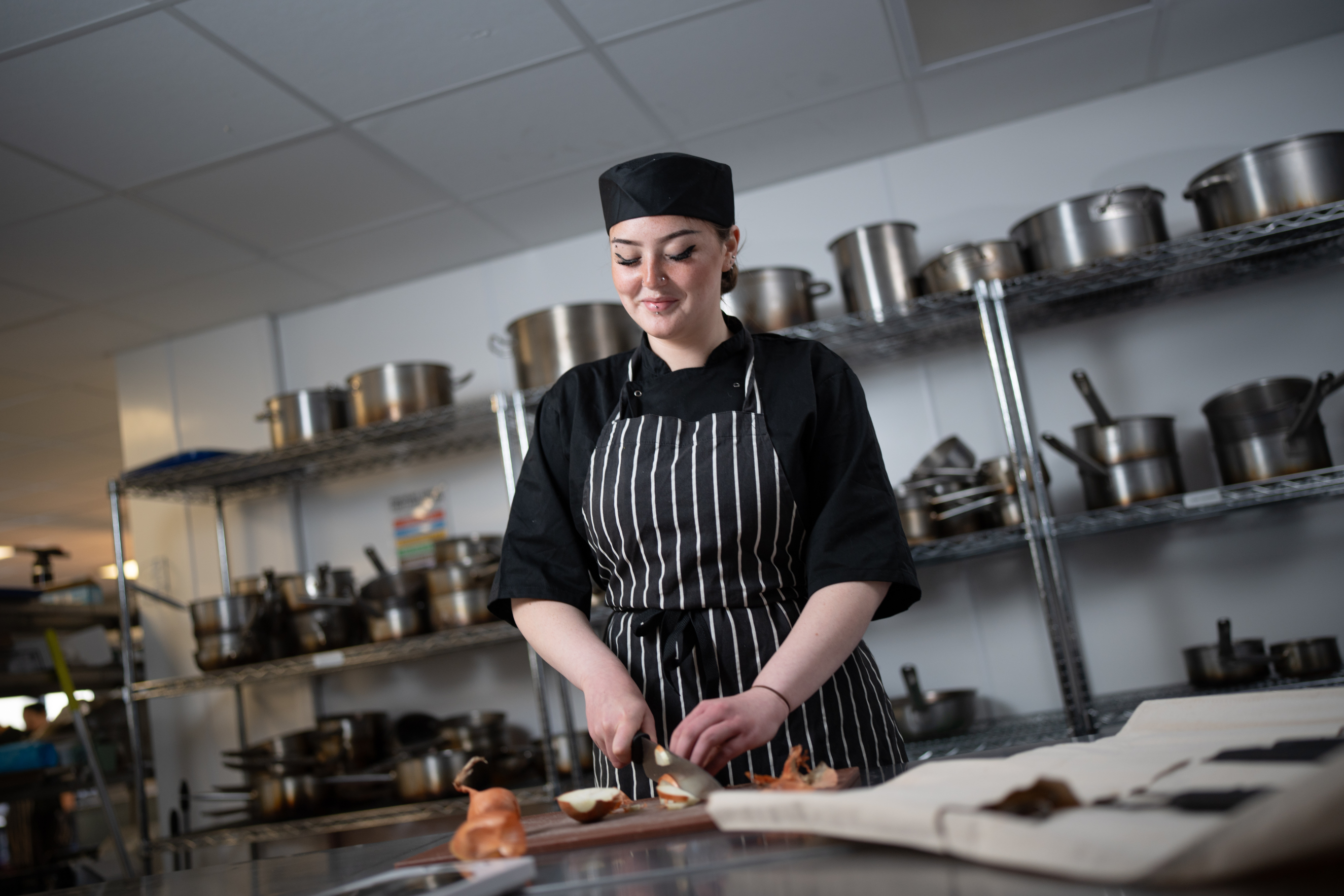 Hospitality student cutting onions in the Weston College kitchen