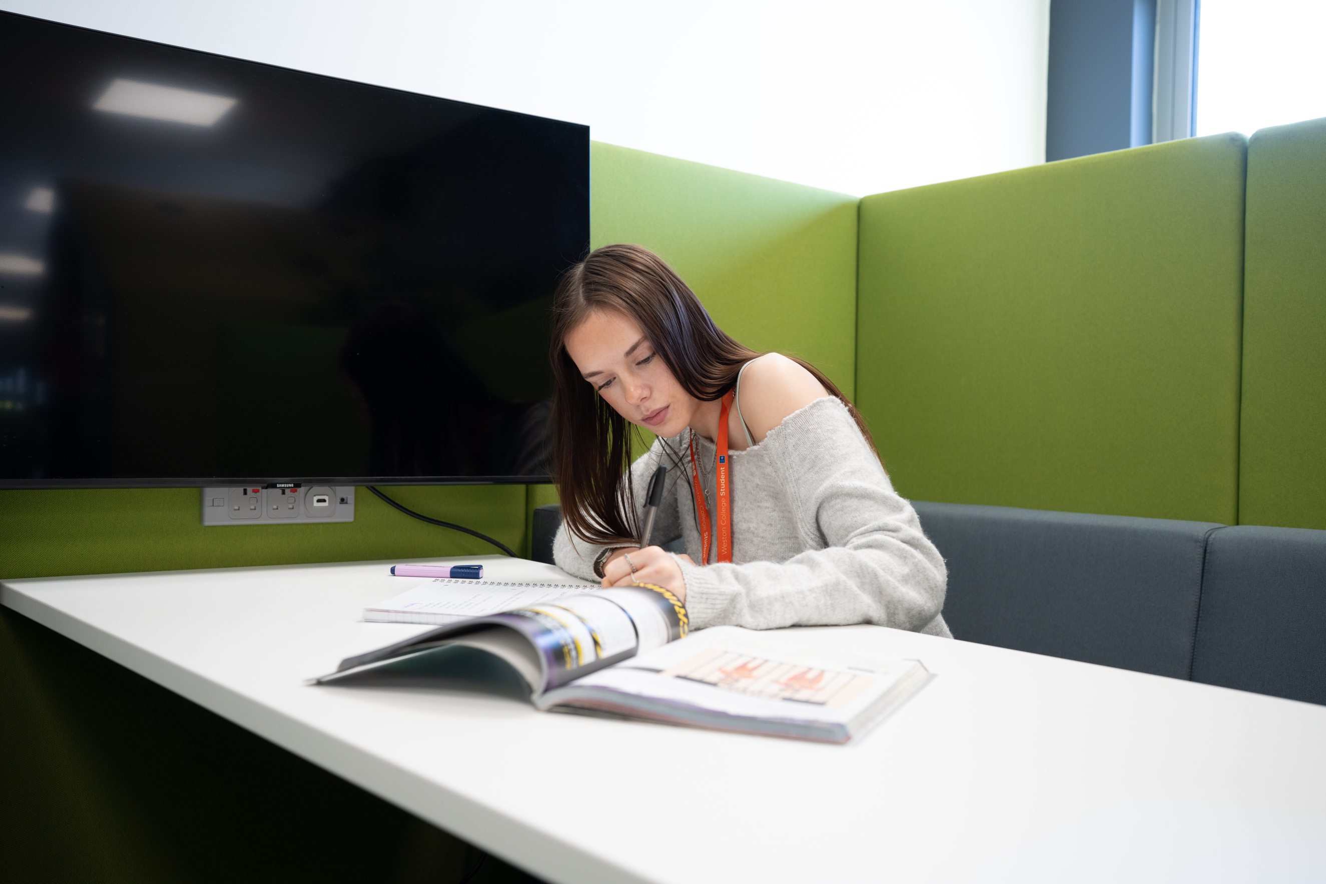 student writing in her workbook in the library