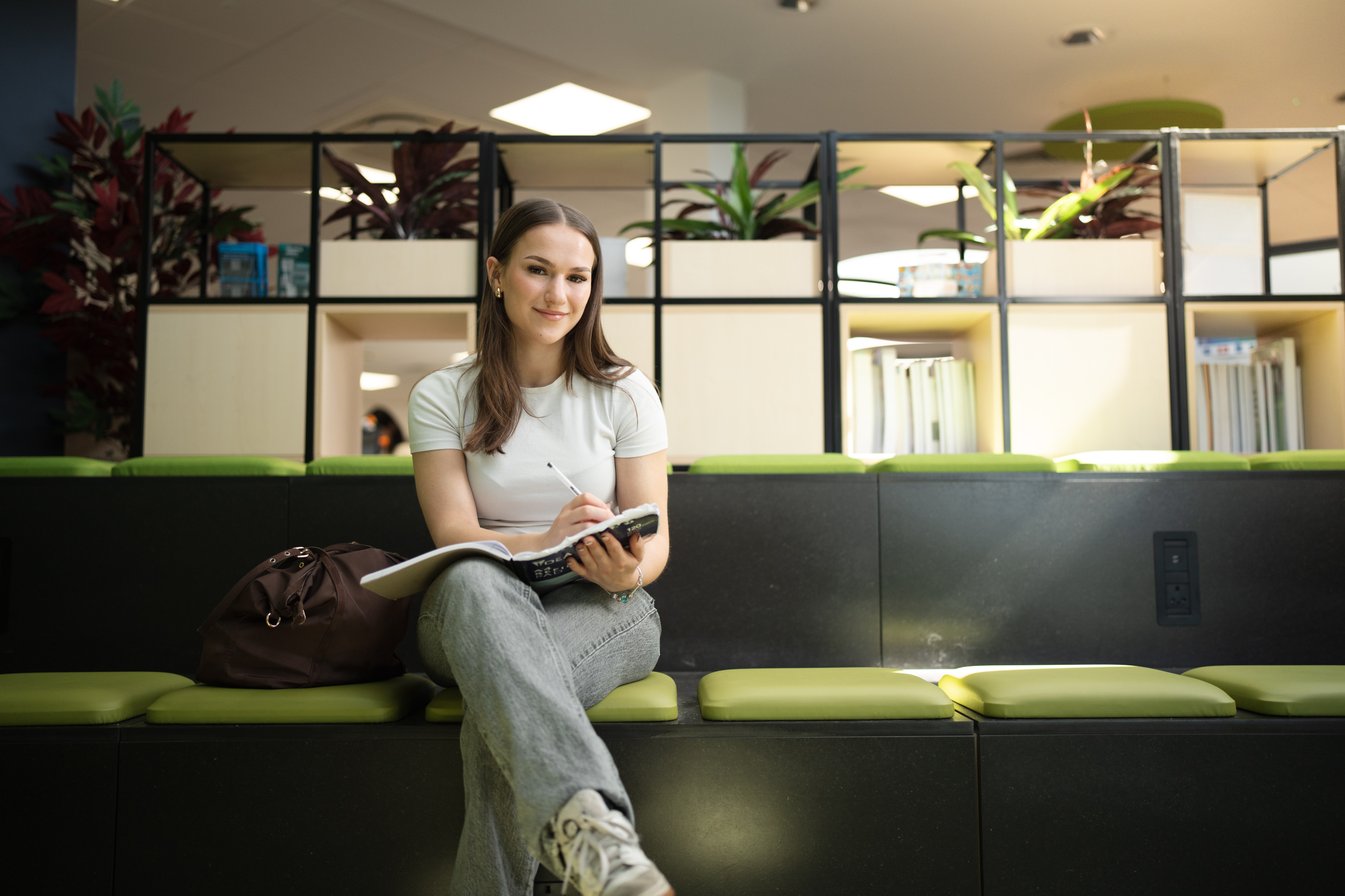 Student sat writing in book smiling