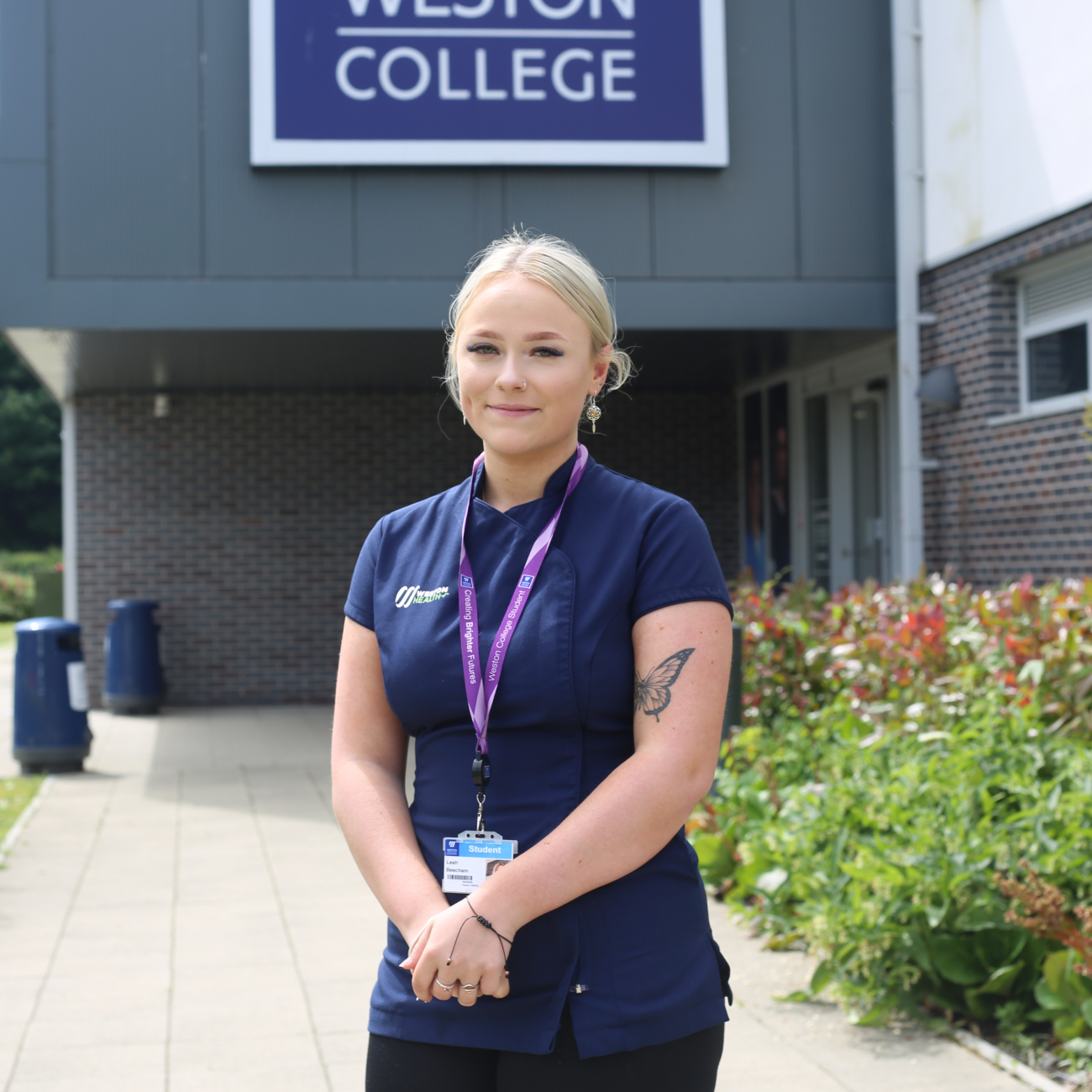 Female Health and Social Student standing in front of College sign 