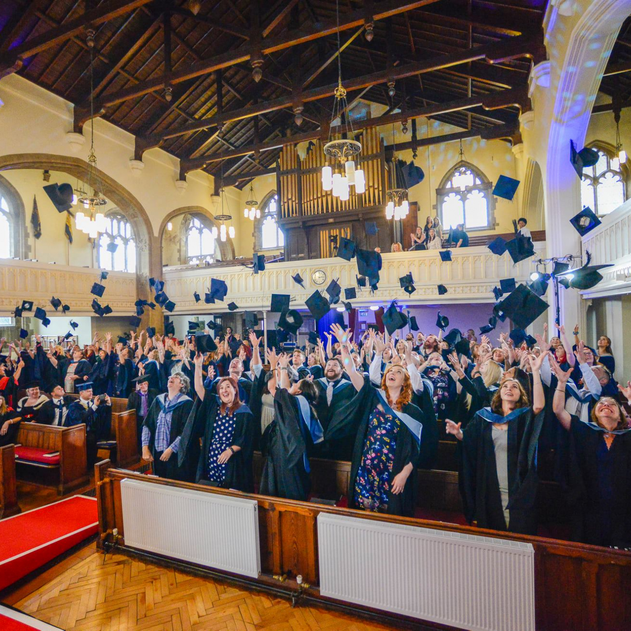 graduates in church throwing motorboard hats in celebration