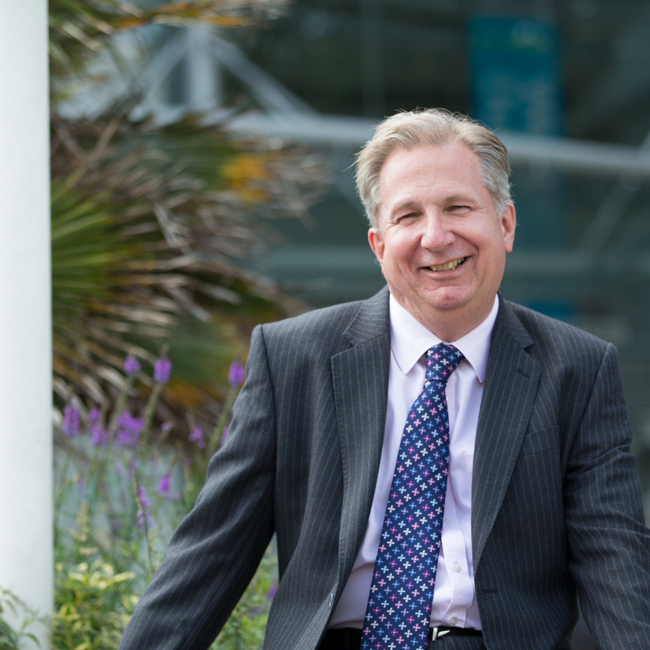 Dr Paul sat by flowers and smiling