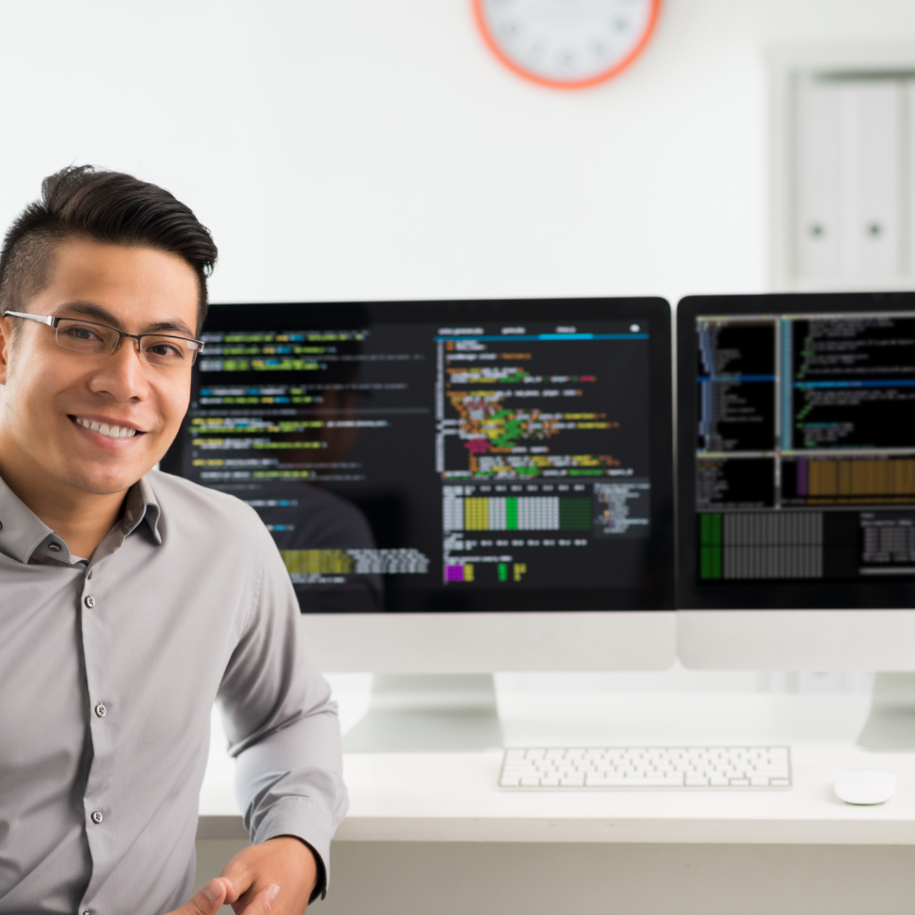 Man smiling and sitting by computer showing code