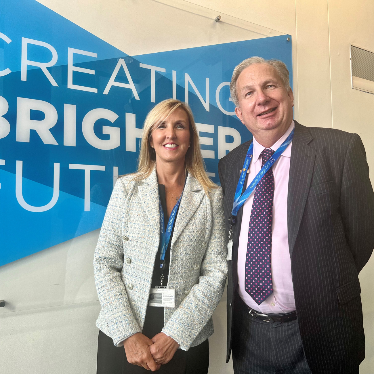 Jacqui Ford and Sir Paul Phillips standing in front of Creating Brighter Futures sign
