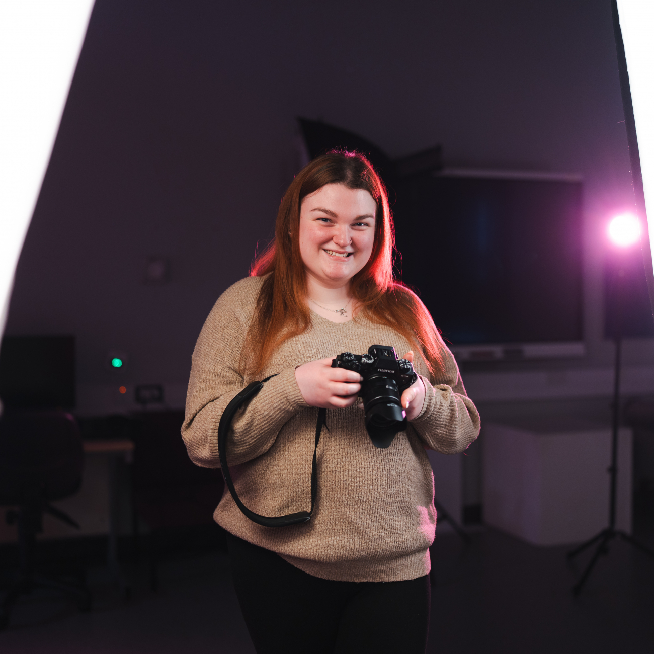 Student smiling holding camera