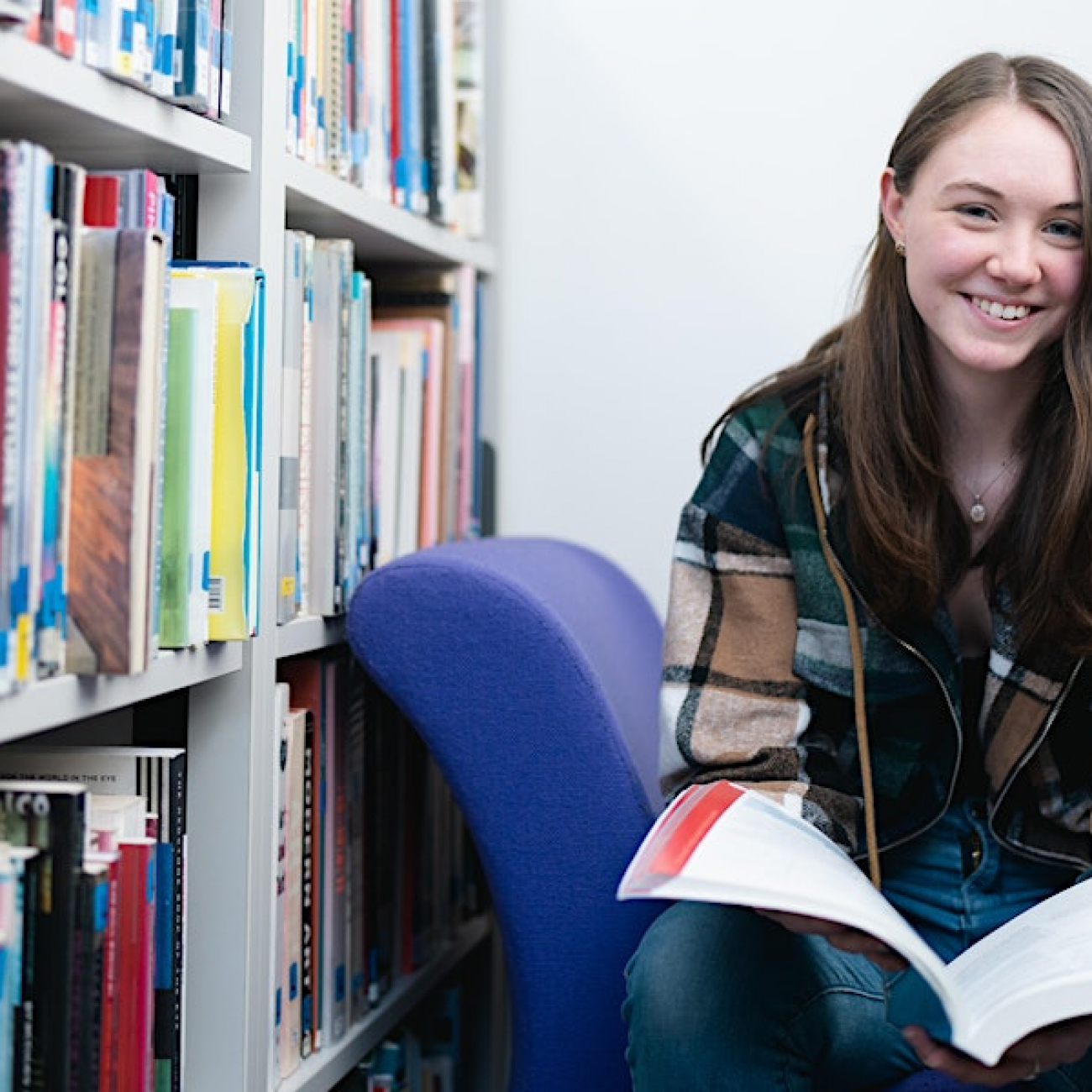 sixth form learner reading a book in the library