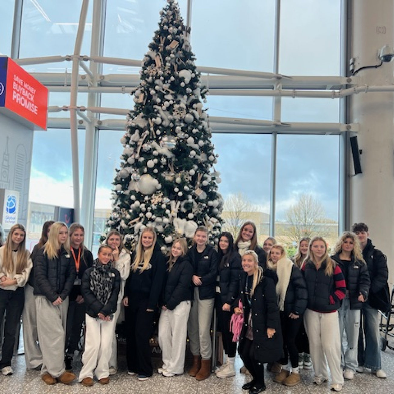 Group photo of students under a Christmas tree at Bristol Airport