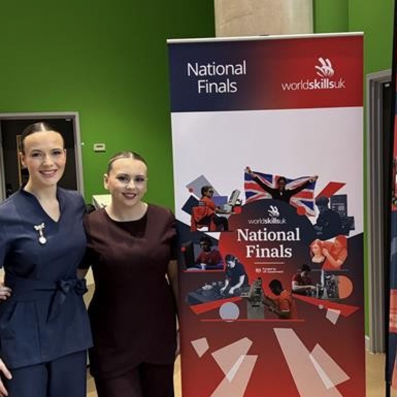 Maddie and Ellie standing by the WorldSkills banner