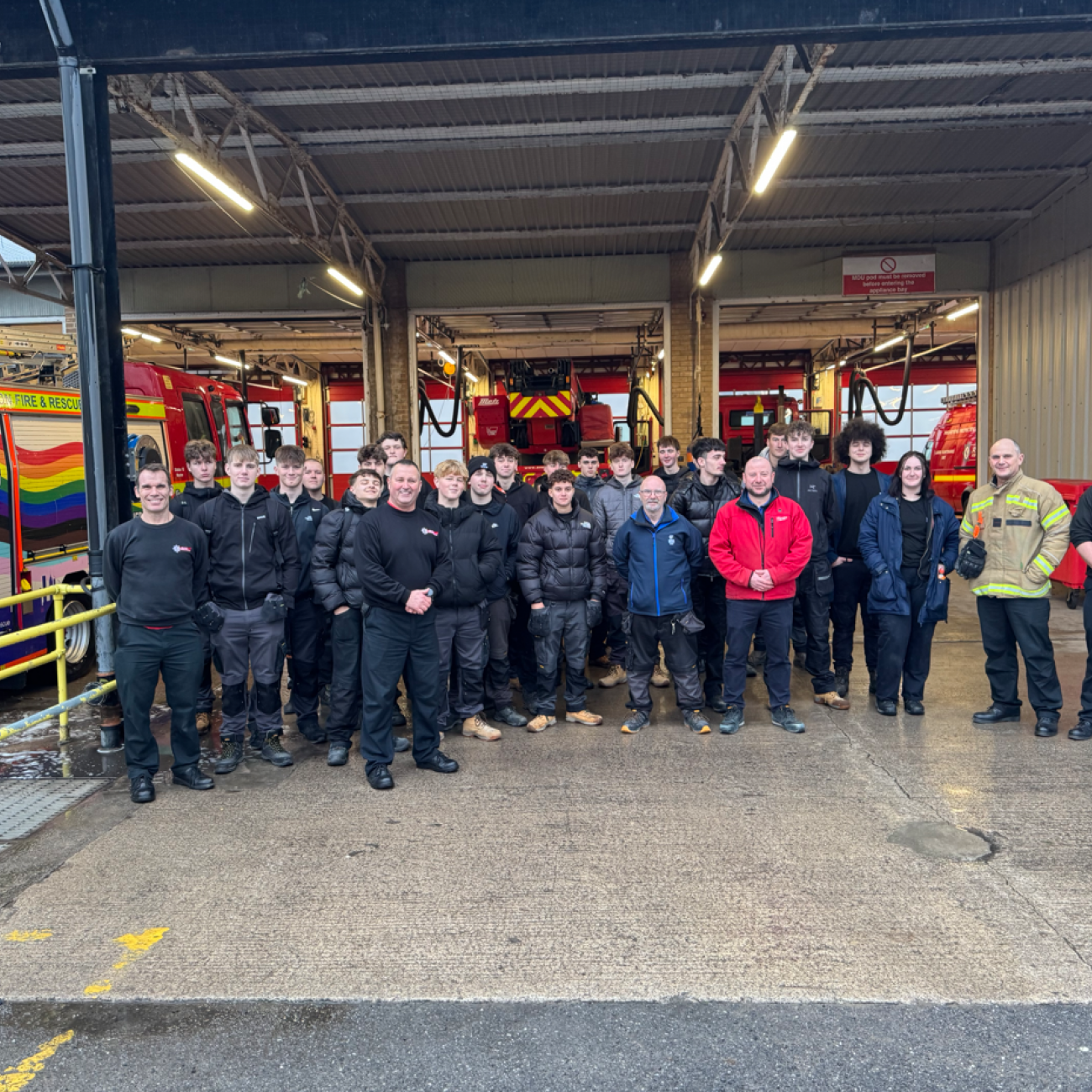 Group photo of electrical students, lecturers, and the firefighters in front of the fire engines
