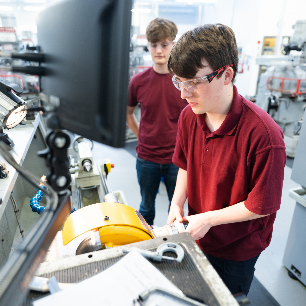 Two students working an engineering machine