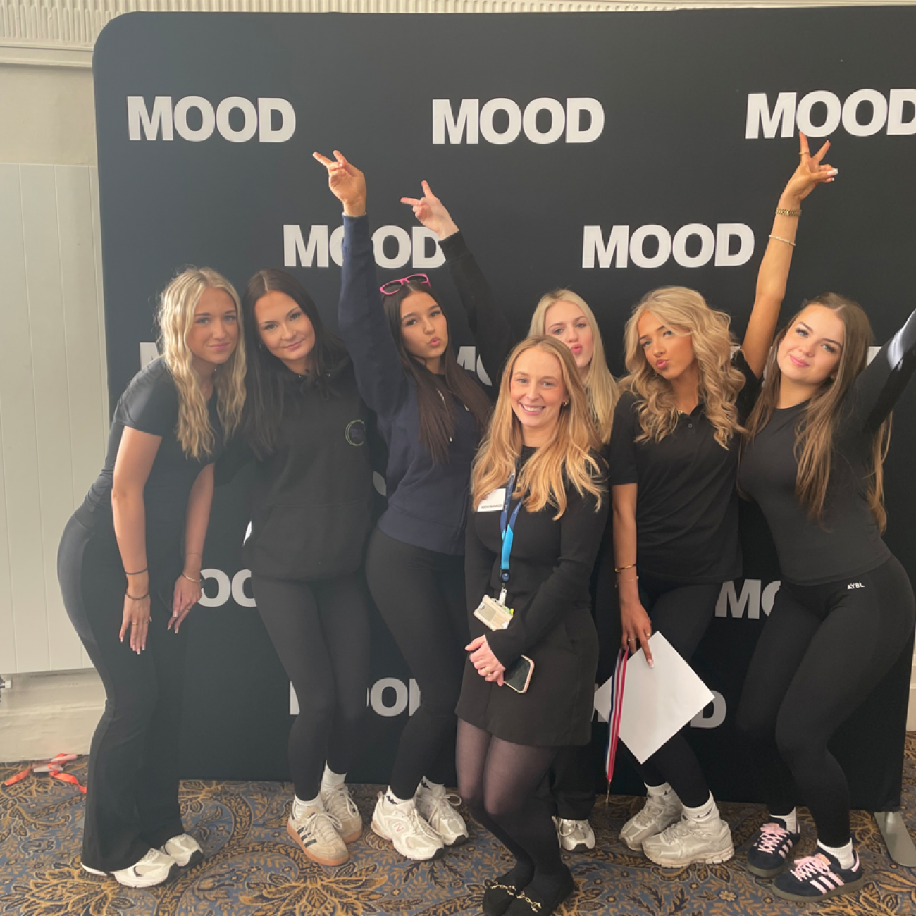 Group of students smiling in front of sponsored backdrop