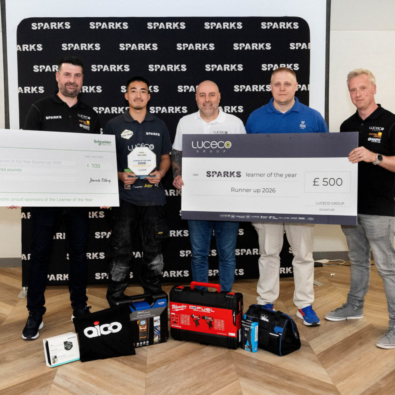 Marcus holding cheque and prizes with 4 industry professionals
