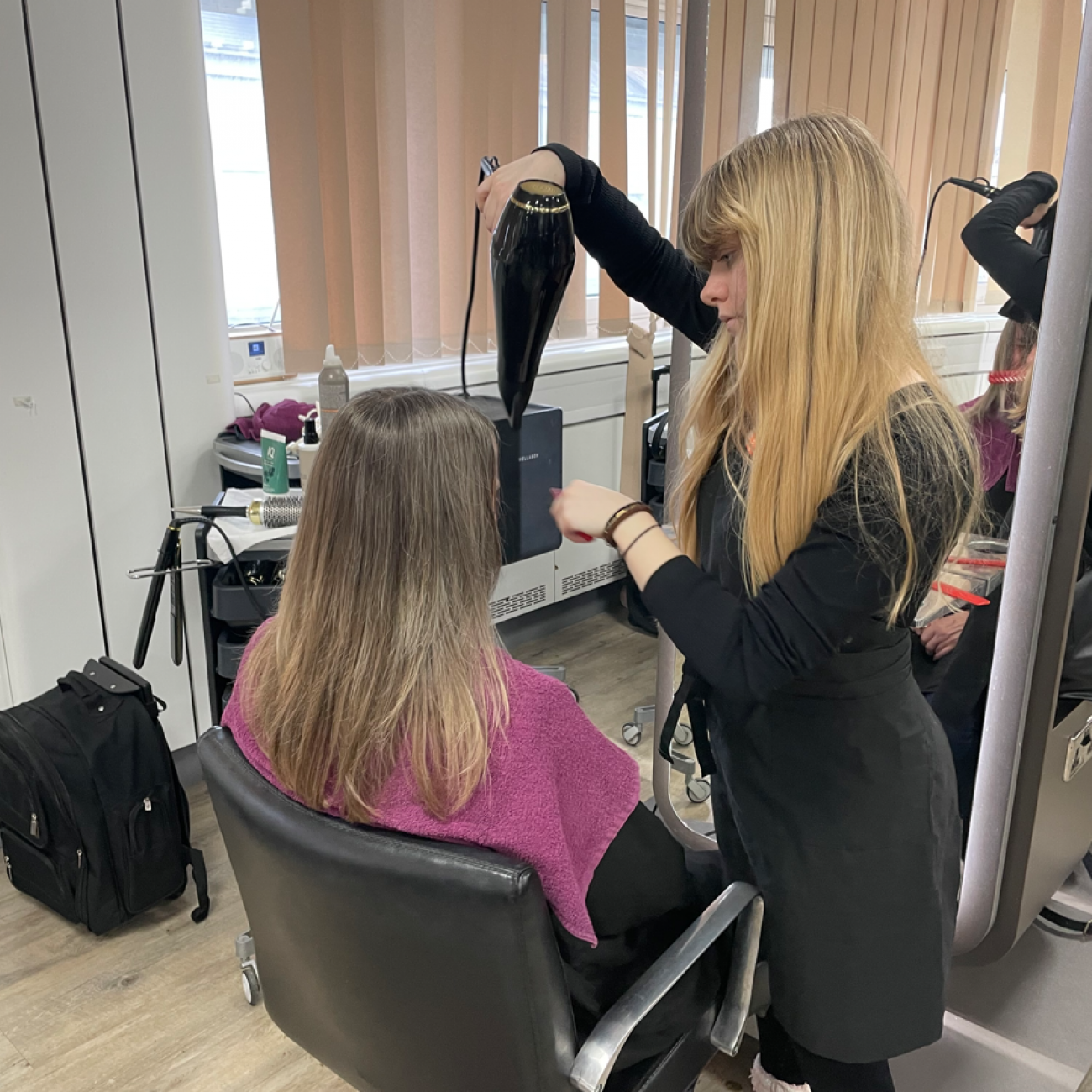 Student blow-drying a member of the public's hair