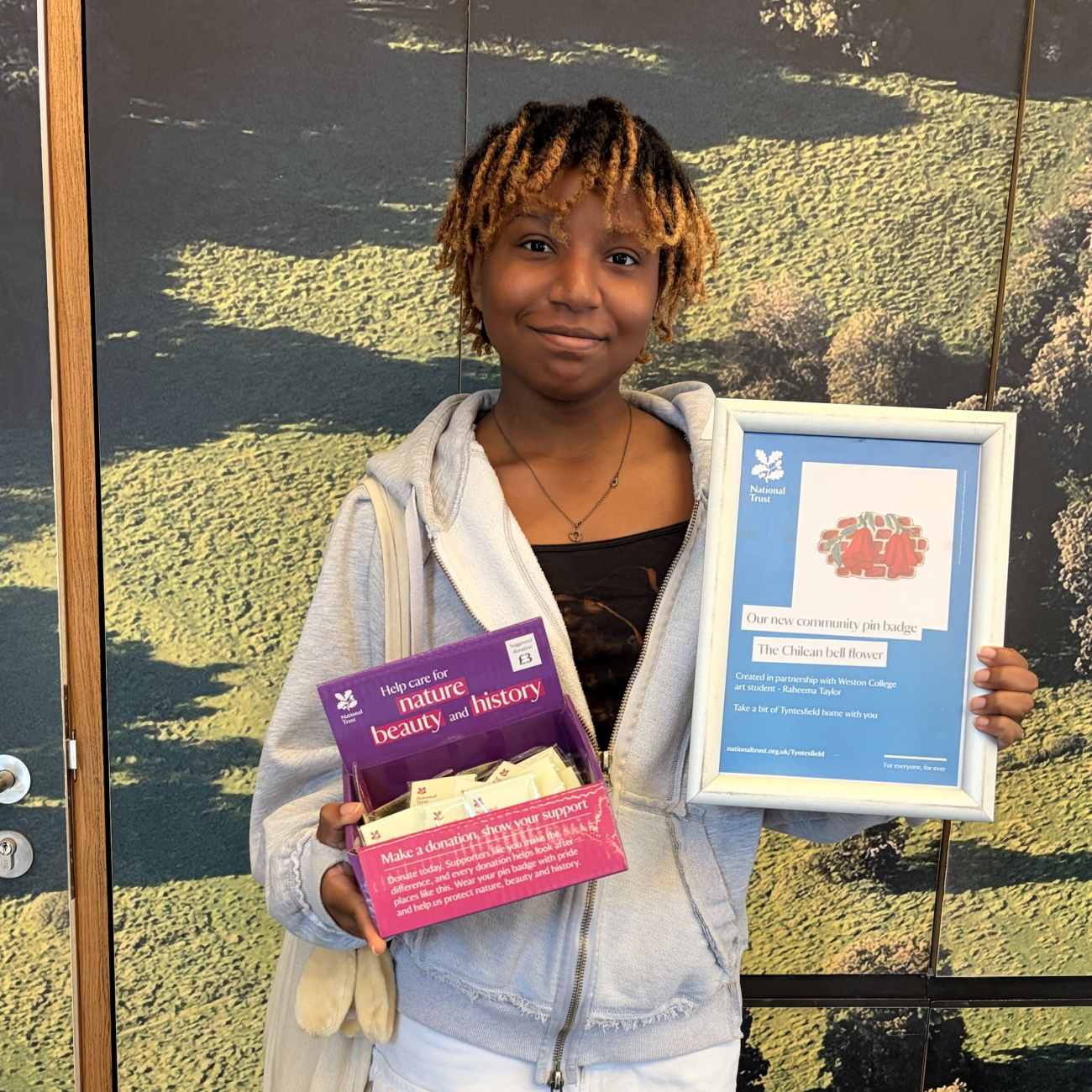 Student, Raheema, standing with a certificate and her pin badges