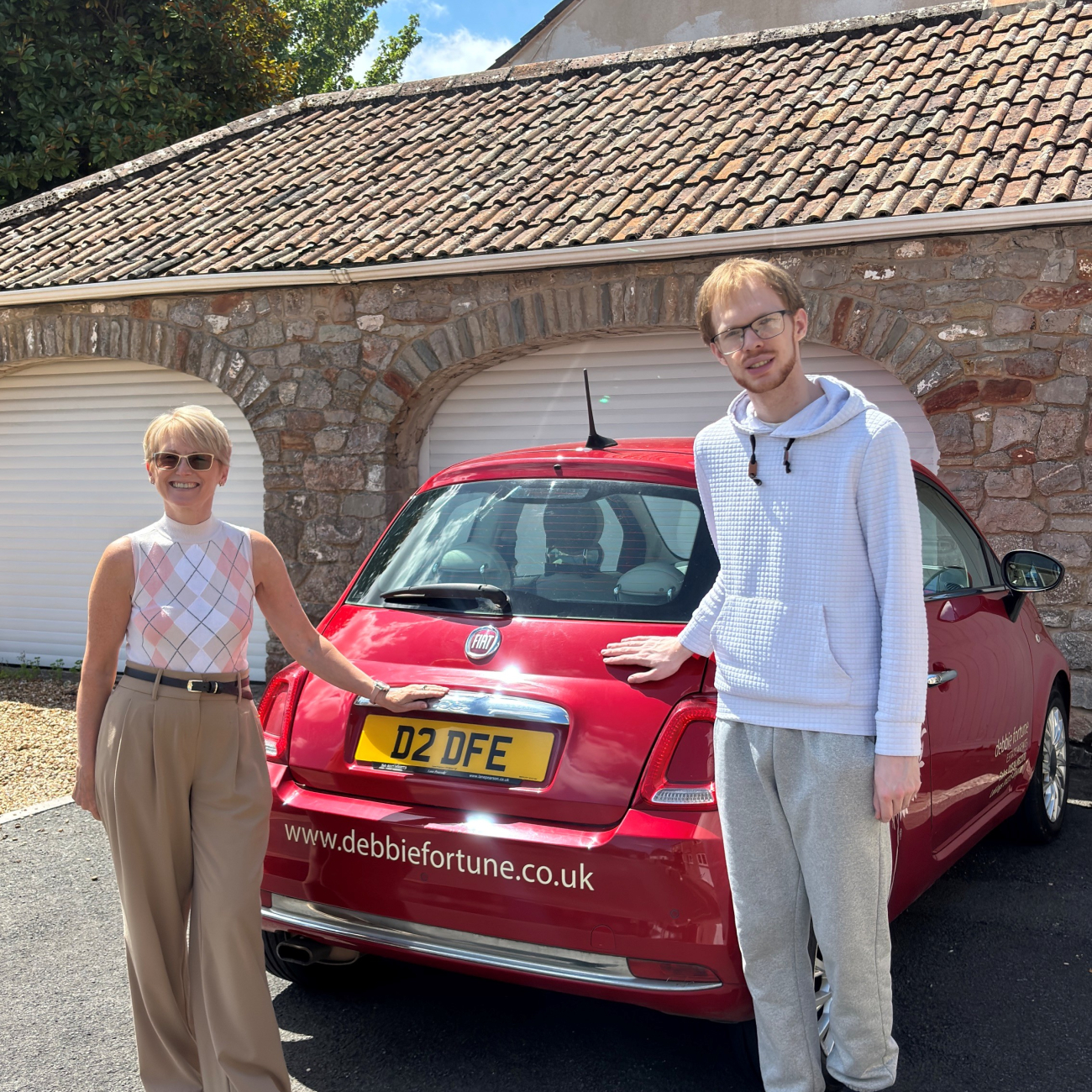 Jo and Kyle stood smiling by a debbie fortune estate agents car