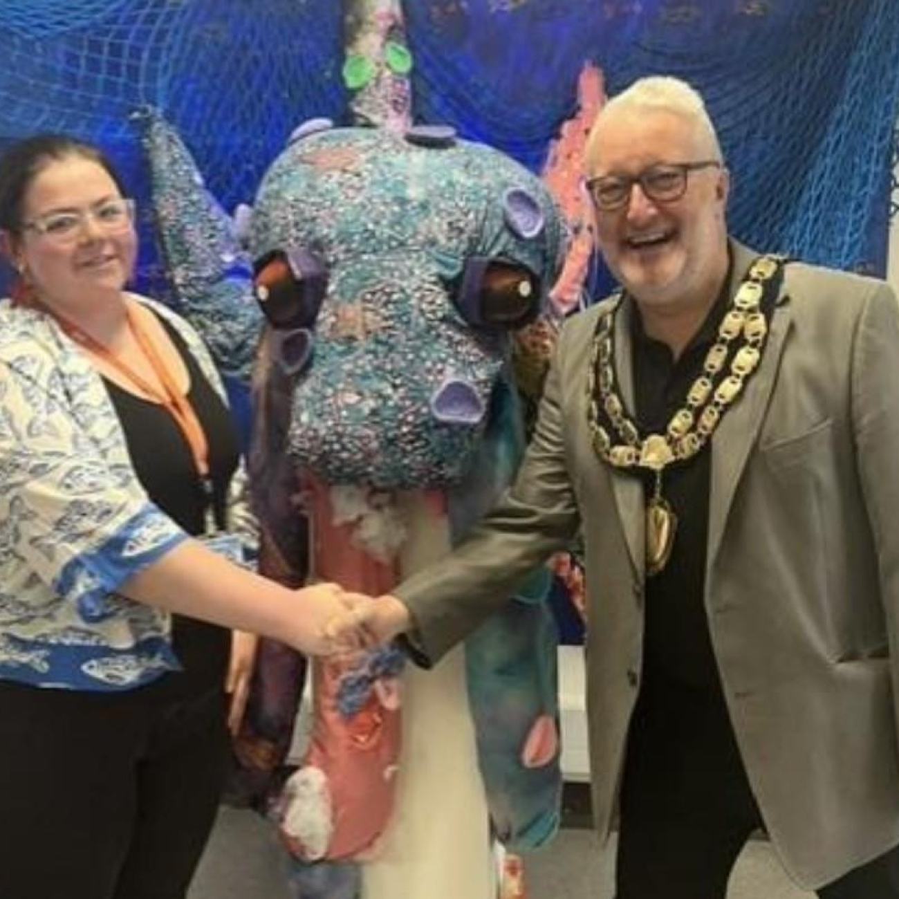 Shannon shaking hands with the mayor in front of her sculpture
