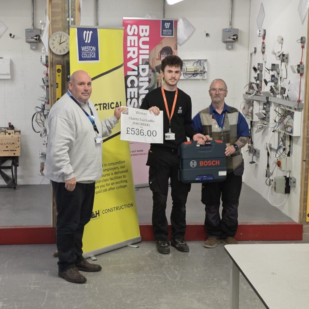 Head of Construction, Richard Hanney, lecturer, Neil Adams, and winner of the raffle smiling for a photo with the Bosch Drill