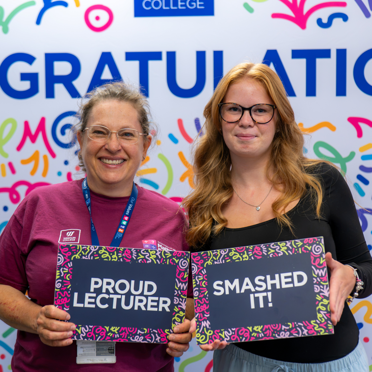 Student and Lecturer holding sings saying: Proud Lecturer and Smashed It