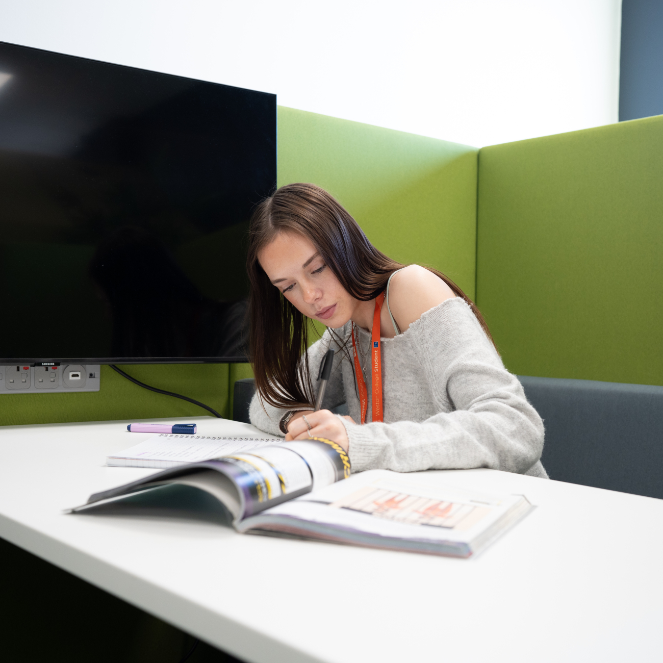 student writing in her workbook in the library