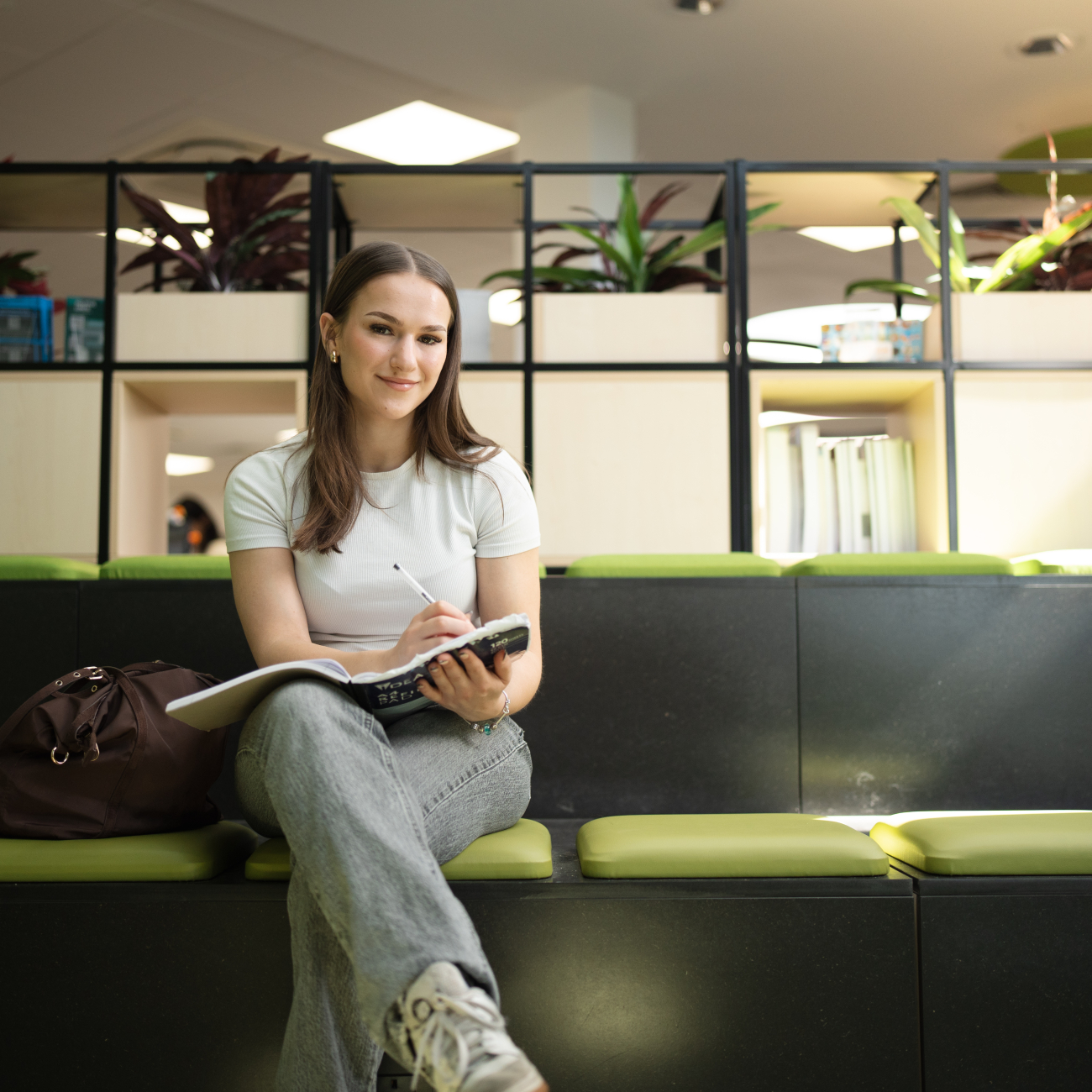 Student sat writing in book smiling
