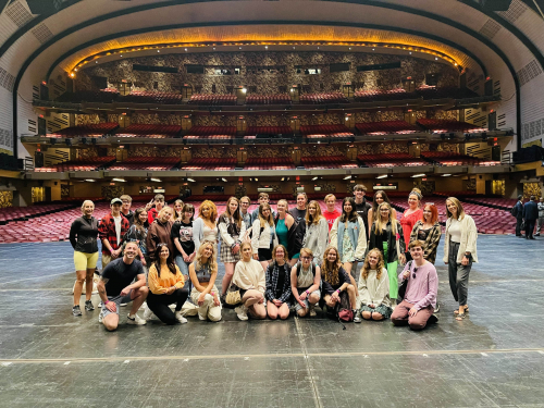 performing arts students stood on stage in broadway theatre