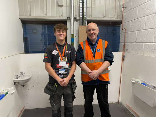 Will and lecturer, Chris, standing smiling in the practice workshop